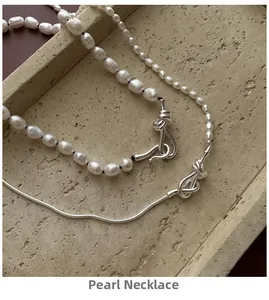 Detailed view of baroque pearl necklace with a unique silver knot clasp on marble