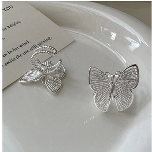 Detail of silver S925 butterfly ear cuffs with intricate hollow mesh wing craftsmanship