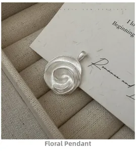 Makroaufnahme des silbernen Rosenanhängers mit mattem Finish in einer beigen Schmuckschatulle