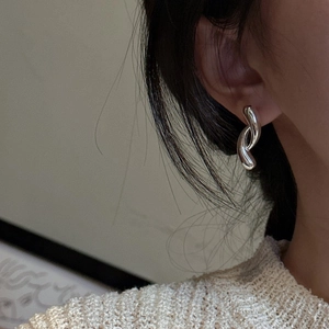 Minimalist S925 sterling silver curved crossover hoop earrings worn by a model