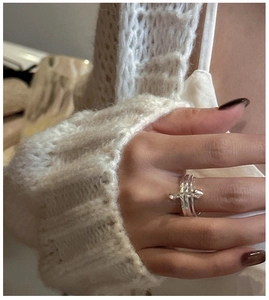 Detail of S925 silver triple-band ring with a unique safety pin design worn on a finger