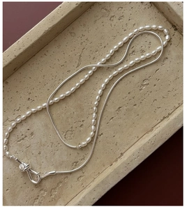 Detail of S925 silver double-layered pearl necklace with a modern knot-shaped clasp