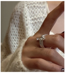 Close-up of S925 silver safety pin heart ring worn against a white knit sweater