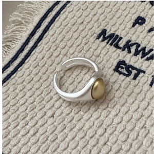 Macro detail of bicolored matte silver ring with golden dome on a textured fabric