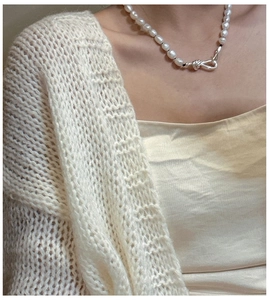 Detail shot of a S925 silver knot clasp on a white freshwater pearl necklace over knitwear