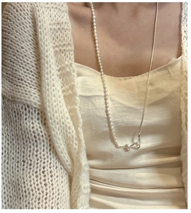 Detail of S925 silver pearl sweater chain with unique knot clasp on an elegant model