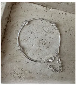 Close-up of polished S925 sterling silver bracelet featuring artistic knotted link design