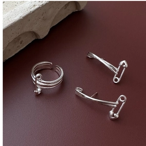 Macro detail of S925 sterling silver safety pin earrings and layered heart ring set