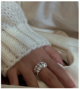 Macro shot of silver croissant ring showing spiral texture on soft knit background