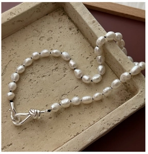 Close-up of S925 silver knot clasp and lustrous white pearls on a minimalist necklace