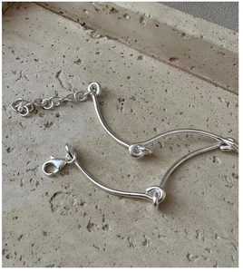 Detail of S925 sterling silver bracelet with curved metal tubes and knot accents