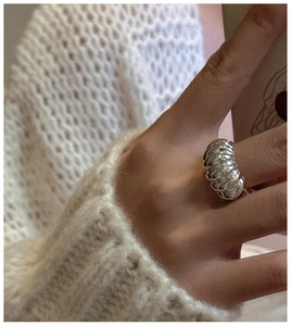 Macro shot of silver croissant ring with textured vertical stripes on finger
