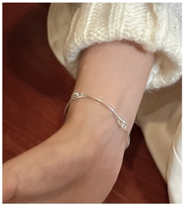 Detail of a minimalist S925 sterling silver knotted bracelet worn on a female wrist