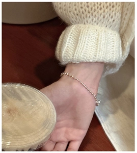 S925 sterling silver bead bracelet worn over a cozy beige knit sweater cuff