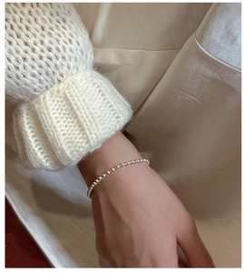 Detail of a minimalist S925 sterling silver beaded bracelet on a model's wrist