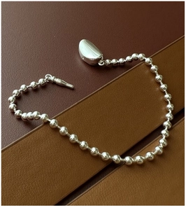 Macro detail of S925 sterling silver bead bracelet with solid bean charm and T-bar clasp