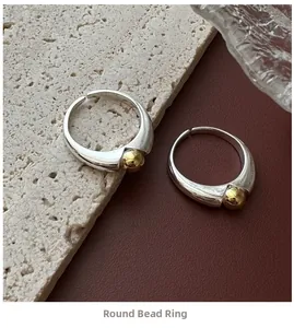 Detail of minimalist S925 silver open ring with a polished golden bead accent