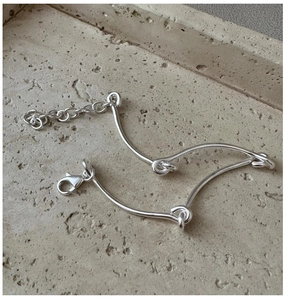 Close-up of polished S925 silver bracelet with knotted tube links and lobster clasp