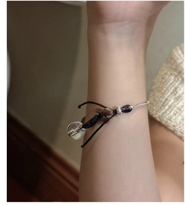 Close-up of retro woven silver bracelet with brown cord and clear bead on a wrist