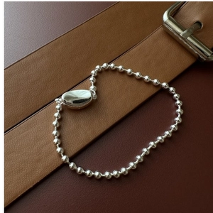 Detail of silver bead bracelet with polished oval buckle on brown leather