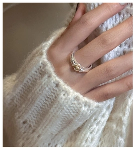 Close-up of a two-tone S925 sterling silver ring with gold bead on a cozy knit background