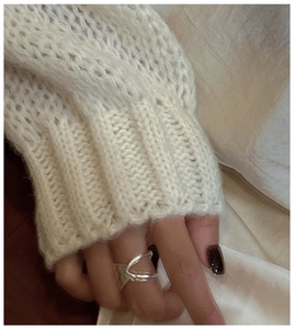 Detail of silver irregular double-layer open ring on hand with knit sweater texture