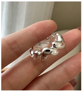 Macro shot of silver liquid metal texture ring showing high-polished wavy heart design