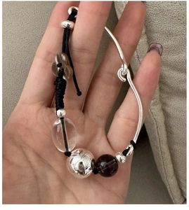 Detail of S925 silver woven bracelet featuring a crystal bead and floral charm decoration