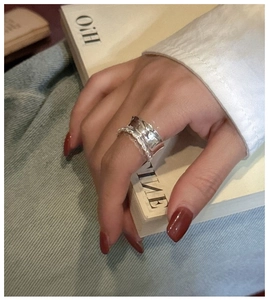 Macro detail of wide silver lace ring with textured edge worn on the index finger