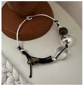 Detail of S925 sterling silver braided bracelet with smoky quartz and polished metal beads