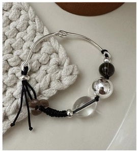 Detail of S925 sterling silver braided bracelet with beads on a woven surface