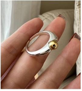 Detailed macro view of S925 sterling silver ring with two-tone gold bead and open band