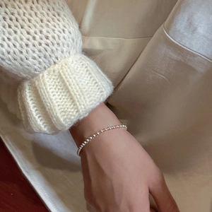 Minimalist S925 sterling silver beaded bracelet for women on a cozy knit sleeve background
