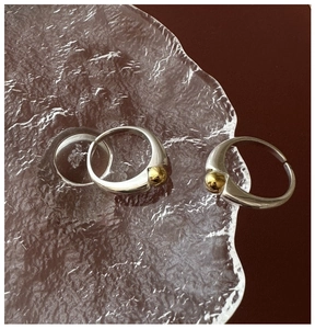 Detailed view of S925 sterling silver rings with gold bead accent on textured glass
