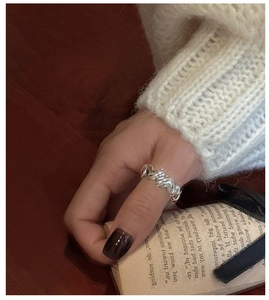 Close-up of S925 sterling silver heart ring with twisted texture on a warm knit background