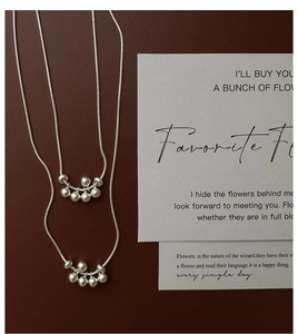 Detail of silver S925 snake chain necklaces with five polished beads on a dark background