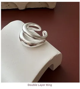 Close-up of a double-layered polished silver ring displayed on a modern white stone stand