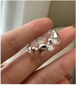 Close-up of heart-shaped fluid silver ring on hand with polished metallic texture