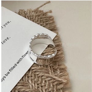 Macro shot of silver wide band ring with scalloped edges on vintage paper background