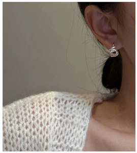 Dettaglio degli orecchini a spirale in argento S925 indossati in uno stile minimalista