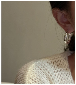 Gros plan d'une boucle d'oreille créole en argent minimaliste portée par un mannequin