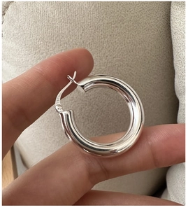 Gros plan d'une boucle d'oreille créole en argent S925 poli avec poinçon d'authenticité