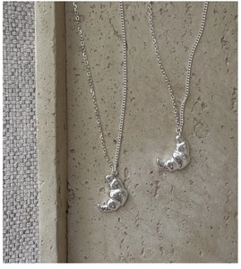 Detailed view of two S925 sterling silver croissant necklaces with textured finish