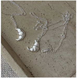 Detail shot of the S925 sterling silver croissant pendant with realistic food texture