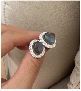 Macro detail of S925 silver labradorite stud earrings held in hand for scale