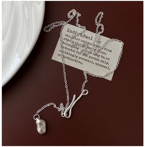 Macro detail of silver minimalist necklace with matte texture on deep red background