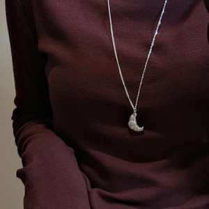S925 sterling silver croissant pendant necklace with textured finish on red garment
