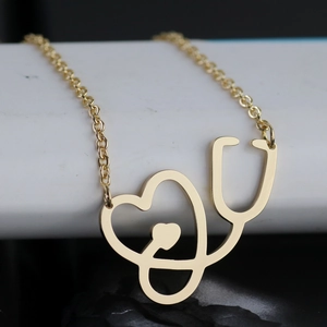 Gepolijste gouden stethoscoop hart ketting hanger op een minimalistisch wit display