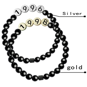 Detail of beaded bracelets with high-shine black stones and 1996 1998 birth year charms