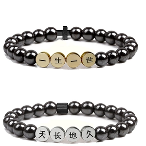 Close-up of engraved Chinese characters on hematite beads of couple bracelets